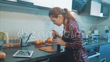 那个女孩把胡萝卜揉在数字平板<strong>电</strong>脑上的<strong>烤盘</strong>上。 美丽的女人在烹饪和测试食物